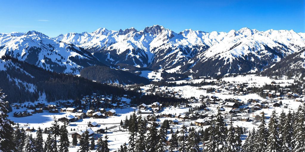 Skiåkere i Alpene med snødekte fjell og hytter